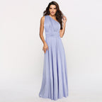 Femme portant une robe longue violette asymétrique élégante, posant sur fond blanc. Mode féminine, tenue de soirée chic, style moderne.