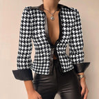 Veste à motif pied-de-poule noir et blanc, manches retroussées, portée avec un pantalon en cuir noir, collier pendentif argenté.