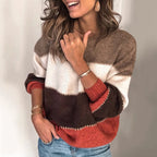 Femme souriante portant un pull tricolore marron, beige et rouge, manches retroussées, avec des bracelets dorés, posant décontractée.