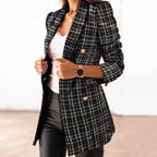Femme portant un blazer en tweed noir et blanc à boutons dorés, chemise blanche, pantalon noir, montre élégante; mode chic et tendance.
