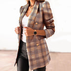 Femme portant un blazer à carreaux beige, chemise blanche et pantalon noir, accessoirisé d'une montre noire. Mode élégante et tendance.