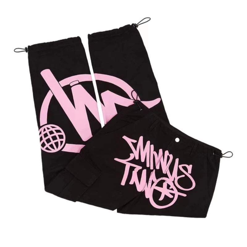 Pantalon noir streetwear avec motifs graphiques roses, style urbain tendance, cordons de serrage, idéal pour mode jeune et décontractée.