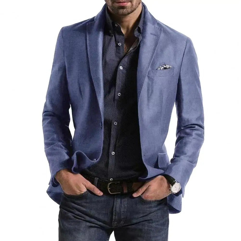 Homme portant une veste bleue élégante sur une chemise à motifs, mains dans les poches, style décontracté chic, montre au poignet gauche.