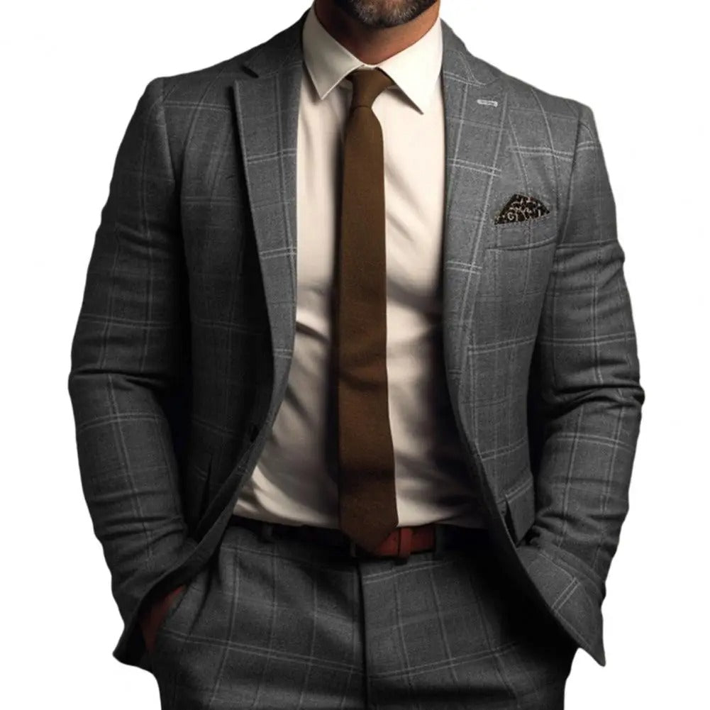 Homme en costume gris à carreaux, cravate marron, chemise blanche, posant avec assurance. Mode masculine élégante, style professionnel.