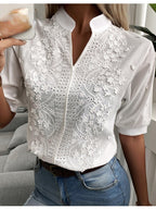 Blouse blanche en dentelle florale, manches courtes, col montant, portée avec un jean bleu. Mode féminine élégante et chic.