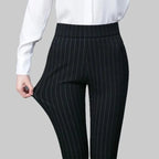 Pantalon noir à rayures verticales porté avec chemise blanche, mode élégante pour femme, tenue professionnelle, style bureau chic.