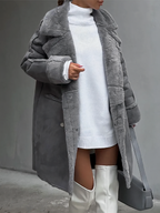 Femme portant un manteau en fausse fourrure gris, robe pull blanche et bottes hautes blanches, tenant un sac à main gris. Mode hiver élégante.