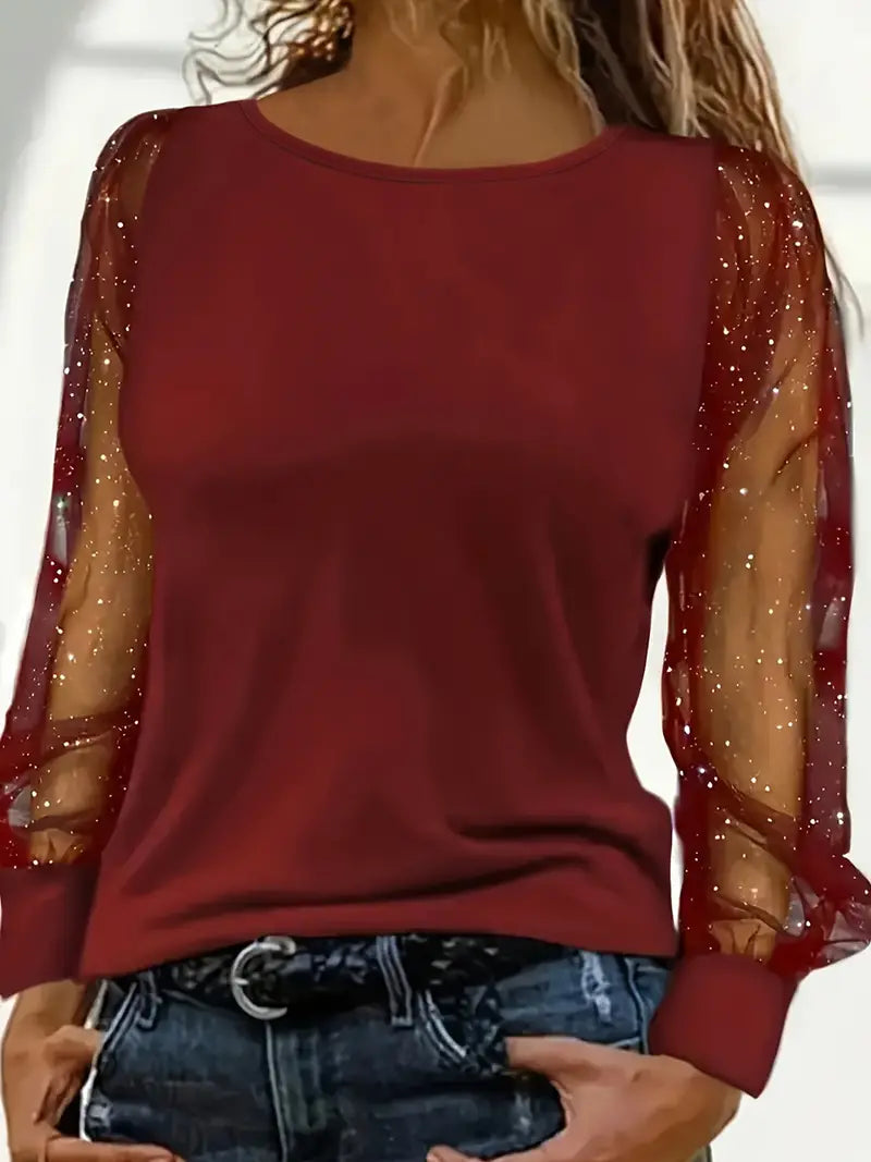 Haut rouge à manches longues transparentes avec paillettes, porté par une femme. Mode élégante, tendance automne, style chic décontracté.