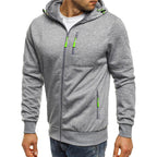 Homme portant un sweat à capuche gris avec fermetures éclair vertes, mode décontractée, vêtement tendance pour homme, style urbain moderne.