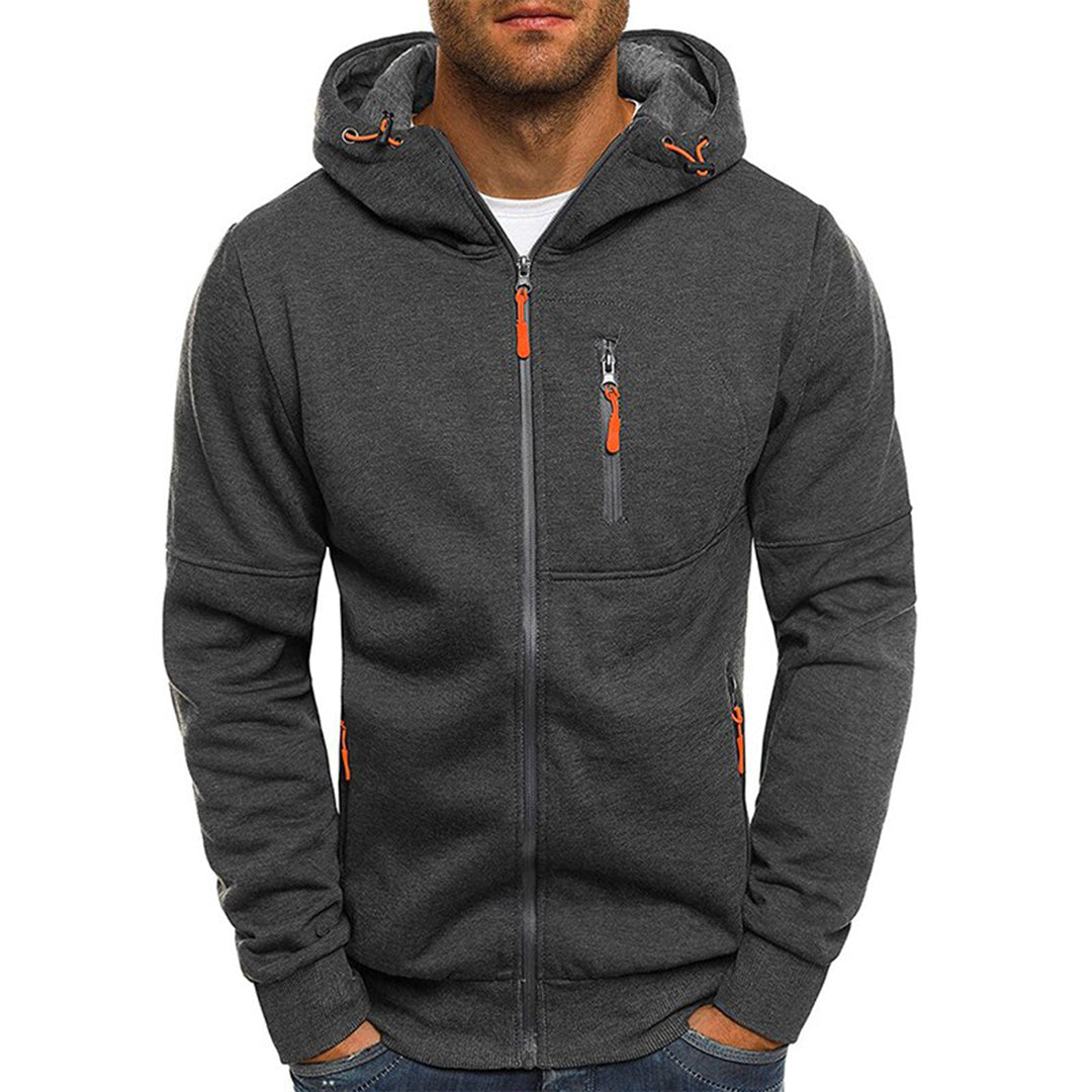Homme portant un sweat à capuche gris foncé avec fermeture éclair et poches zippées orange, mode décontractée, vêtement automne-hiver.