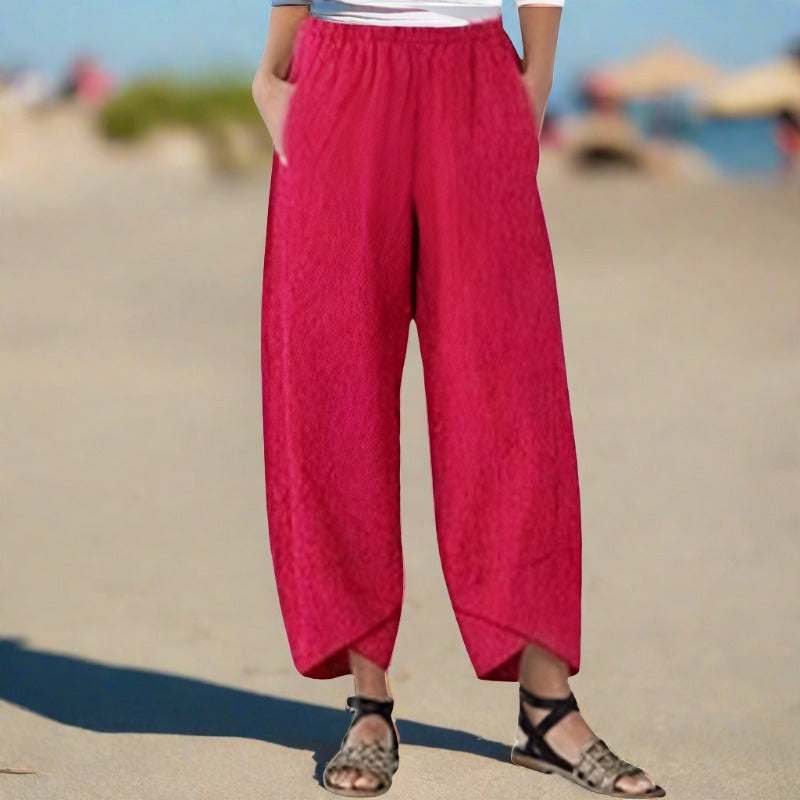 Pantalon ample rouge pour femme sur plage, style décontracté, tissu léger, idéal pour l'été. Mode féminine, confort, vacances bord de mer.