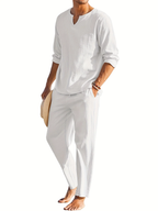 Homme en tenue décontractée blanche, chemise à manches longues et pantalon, tenant un chapeau. Mode estivale élégante et confortable.