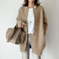 Femme portant un manteau en laine beige, t-shirt blanc, jean gris, sac à main taupe, collier doré. Mode automne chic et décontractée.