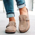 Chaussures mocassins en daim beige pour femme, avec boucle décorative, portées avec un jean retroussé. Mode décontractée élégante.