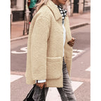 Femme portant un manteau en fausse fourrure beige, chemise blanche, foulard à pois, et jeans gris, marchant en ville. Mode automne-hiver tendance.