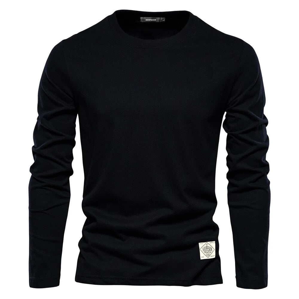 T-shirt noir à manches longues pour homme, col rond, style décontracté, étiquette blanche en bas, idéal pour mode automne-hiver.
