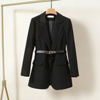 Veste blazer noire élégante avec ceinture, suspendue sur un cintre doré. Mode femme, tenue professionnelle chic, tendance automne-hiver.