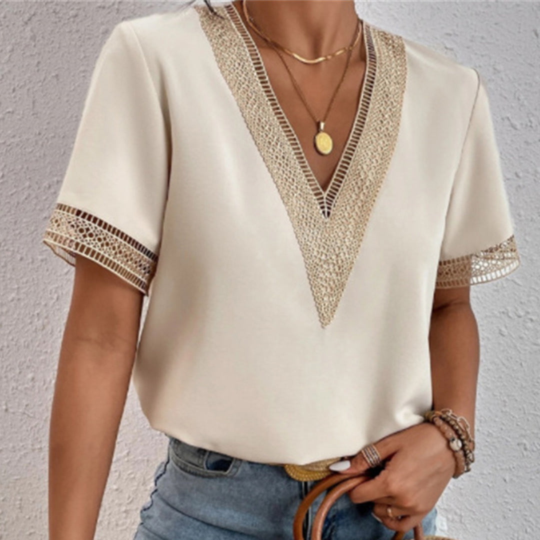 Femme portant un haut blanc à manches courtes avec dentelle dorée, col en V, accessoires en or, et jean bleu. Mode élégante et tendance.