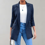 Femme portant un blazer bleu marine élégant, t-shirt blanc et jean ajusté, tenant un sac à main. Mode féminine chic et moderne.