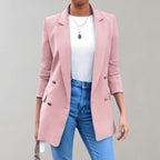 Femme portant un blazer rose élégant, t-shirt blanc et jean bleu, accessoirisée d'un collier pendentif. Mode féminine chic et moderne.
