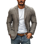 Homme portant une veste en lin gris, t-shirt blanc et jean décontracté, style mode masculine élégante et moderne.
