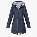 Veste imperméable femme bleu marine avec capuche rayée, cordons ajustables et fermeture éclair. Mode pluie élégante et fonctionnelle.