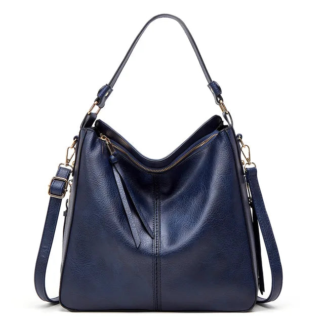 Sac à main en cuir bleu marine avec bandoulière réglable, fermeture éclair dorée et design élégant. Accessoire mode femme chic et tendance.