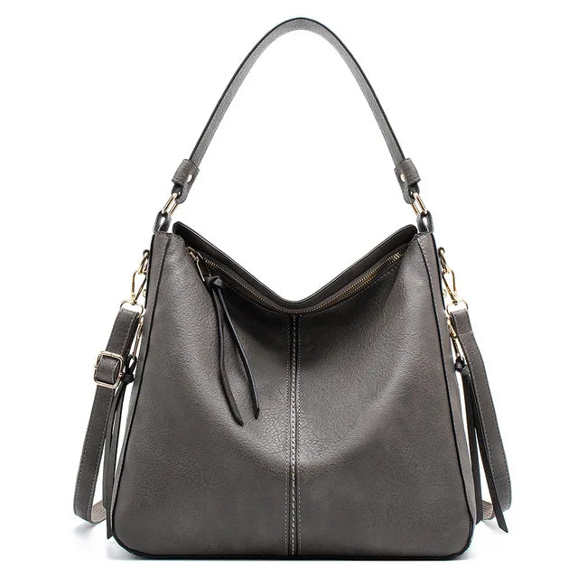 Sac à main en cuir gris élégant avec bandoulière réglable et fermeture éclair, design moderne et spacieux, accessoire mode femme tendance.