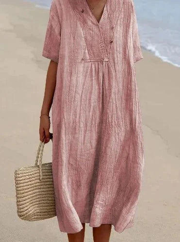 Robe en lin rose ample sur plage, tenue d'été décontractée, mode féminine, sac en osier, style bohème chic, bord de mer.