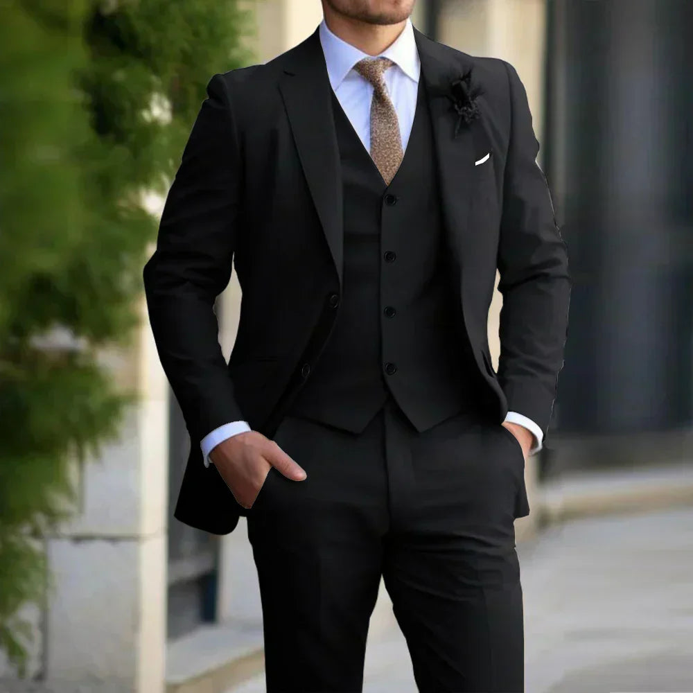 Homme en costume noir élégant avec cravate dorée, posant à l'extérieur. Mode masculine, tenue formelle, style sophistiqué.