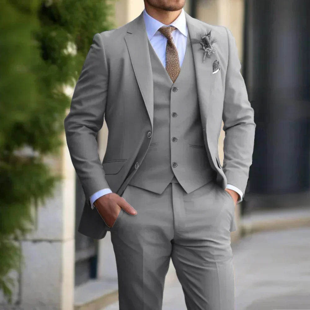 Homme en costume gris élégant avec cravate marron, posant à l'extérieur. Mode masculine, style formel, tenue de bureau chic.