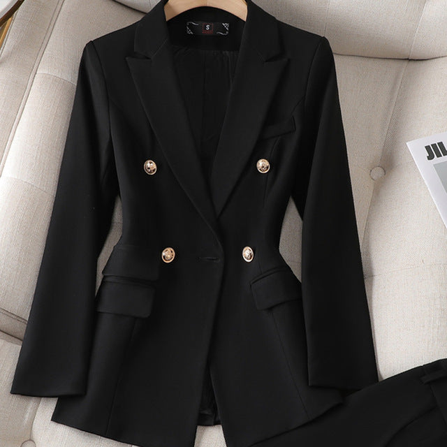 Veste blazer noir élégante à double boutonnage doré, posée sur un canapé beige, style chic et moderne pour femmes, mode professionnelle.