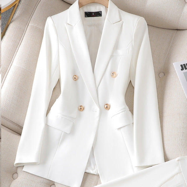 Blazer blanc élégant à double boutonnage en tissu lisse, posé sur un fauteuil beige. Veste chic pour femme, mode professionnelle et tendance.