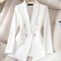 Blazer blanc élégant à double boutonnage en tissu lisse, posé sur un fauteuil beige. Veste chic pour femme, mode professionnelle et tendance.
