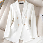 Blazer blanc élégant à double boutonnage en tissu lisse, posé sur un fauteuil beige. Veste chic pour femme, mode professionnelle et tendance.