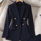 Blazer bleu marine élégant pour femme avec boutons dorés, posé sur un canapé beige. Mode féminine, veste chic, tenue professionnelle.