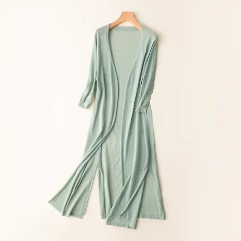 Robe longue en maille verte, manches longues, style décontracté, suspendue sur un cintre en bois, mode féminine élégante et confortable.