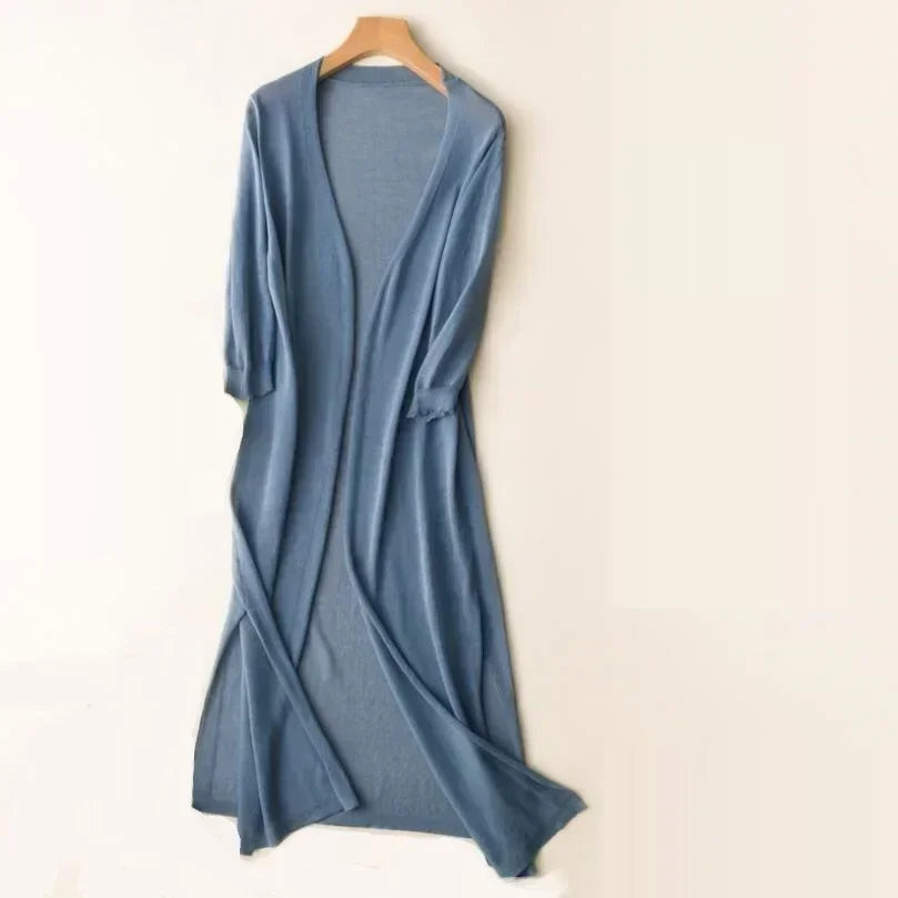 Gilet long bleu en tricot, manches trois-quarts, suspendu sur un cintre en bois. Mode féminine, vêtement élégant, style décontracté.