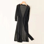 Robe longue noire en tricot léger, manches longues, style cardigan ouvert, suspendue sur un cintre en bois, mode élégante et décontractée.