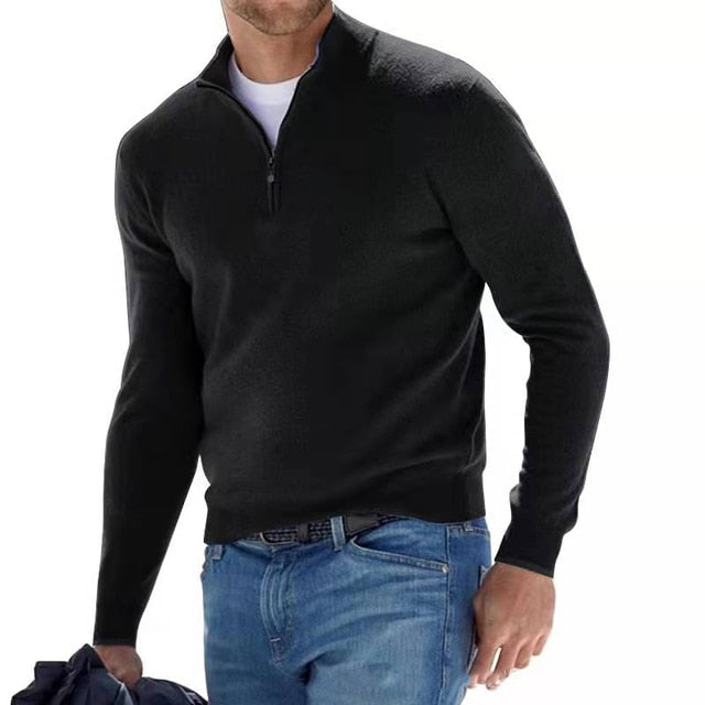 Homme portant un pull noir à col zippé, associé à un jean bleu. Mode masculine élégante, tenue décontractée, style automne-hiver.