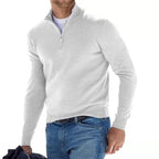 Homme portant un pull blanc à col zippé, tenant une veste, sur fond blanc. Mode masculine, style décontracté, vêtements d'hiver.