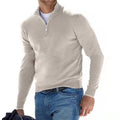 Homme portant un pull beige à col zippé, manches longues, avec un jean bleu. Mode masculine décontractée, style automne-hiver.