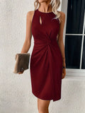 Robe bordeaux élégante sans manches avec découpe, drapée à la taille. Femme tenant une pochette beige devant une fenêtre. Mode chic et tendance.