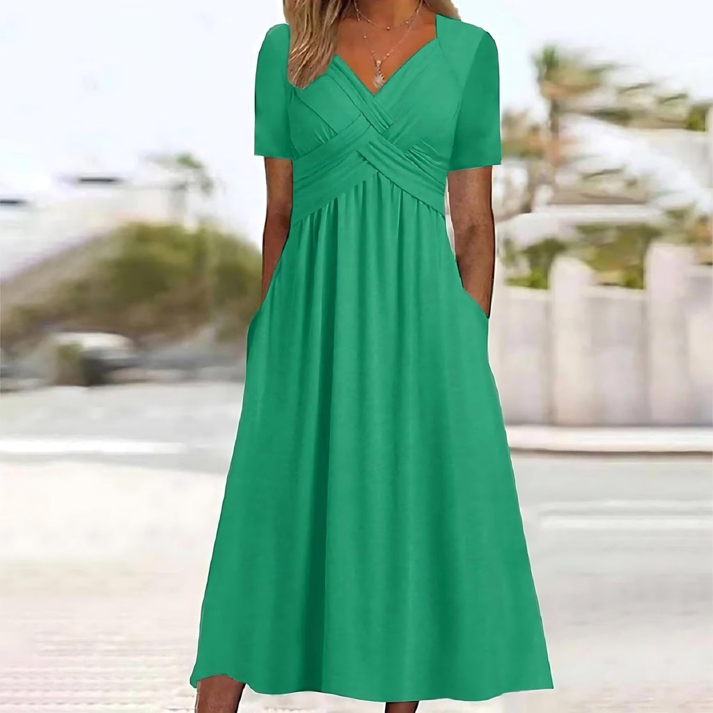 Robe verte élégante avec manches courtes et poches, portée par une femme en extérieur. Mode féminine, tenue estivale chic, style décontracté.