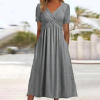 Robe longue grise élégante avec manches courtes et poches, portée par une femme en extérieur. Mode féminine, tenue d'été chic.