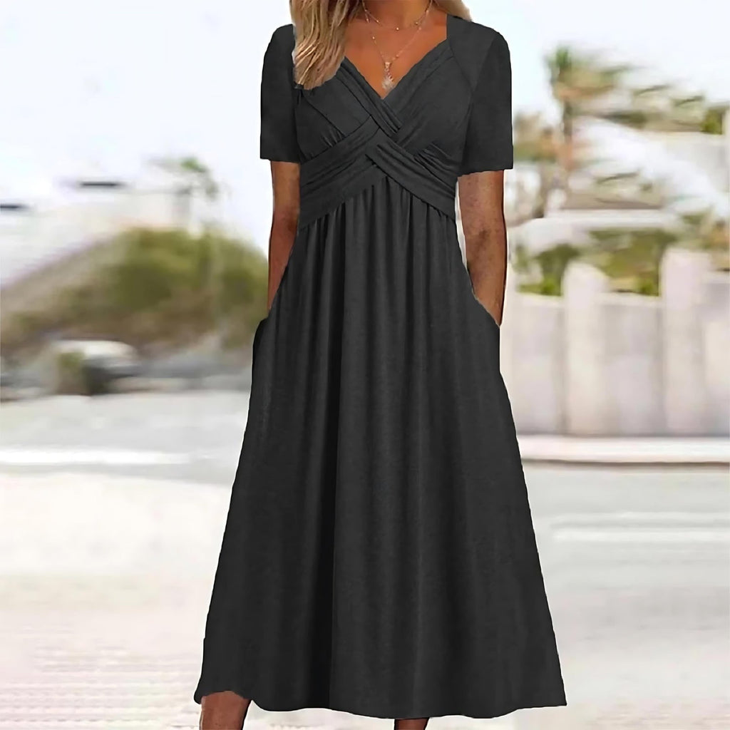 Robe longue noire élégante avec manches courtes et poches, portée par une femme en extérieur. Mode féminine, tenue estivale chic.