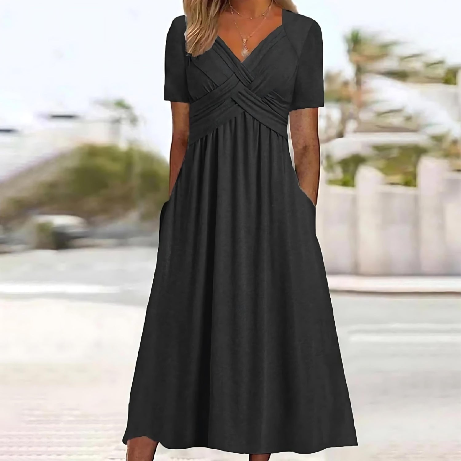 Robe longue noire élégante avec manches courtes et poches, portée par une femme en extérieur. Mode féminine, tenue estivale chic.