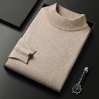 Pull beige en laine à col roulé, soigneusement plié dans une boîte noire, avec une montre-bracelet élégante en acier inoxydable posée à côté.