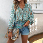Femme en blouse bohème fleurie verte, short en jean, tenant un sac à franges ethnique. Mode estivale, style décontracté chic, accessoires tendance.