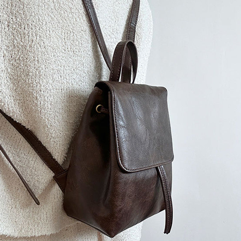 Sac à dos en cuir marron foncé sur fond blanc, porté par une personne. Design minimaliste, élégant et tendance. Accessoire mode incontournable.
